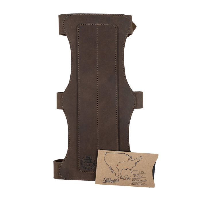 The 3-Buckle Archery Bracer from Valhalla Gear alongside its authenticity card. This artisan piece made from full grain leather represents small batch production in La Antigua Guatemala, designed for archery with adjustable straps for a personalized fit.