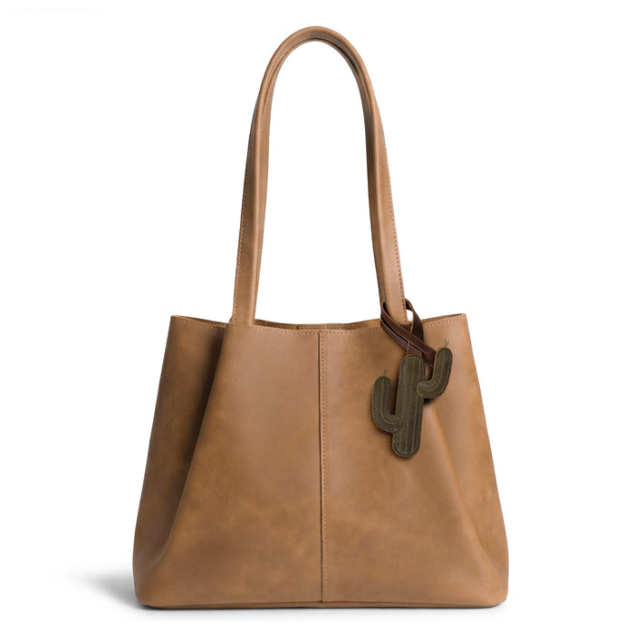 Hide & Drink Bag Charms attached to a trendy brown handbag, displaying a butterfly design ideal for personalization. This accessory serves as a purse charm for tote & backpacks made from high-quality full grain leather, showcasing StockyardX's focus on small batch production. Every piece features hand cut, hand sewn artistry and fire branding, handmade in La Antigua Guatemala & Oaxaca Mexico.