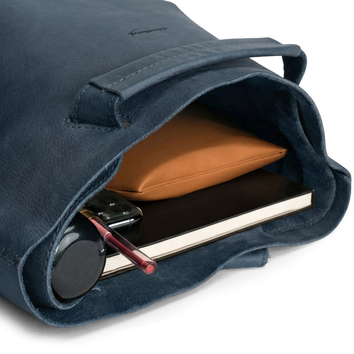 Interior view of Heather's Convertible Backpack to Shoulder Bag, filled with everyday essentials like notebooks and a device. This spacious crossbody for women made from Full Grain Leather embraces small batch production and artisan techniques, handmade in La Antigua Guatemala & Oaxaca Mexico.