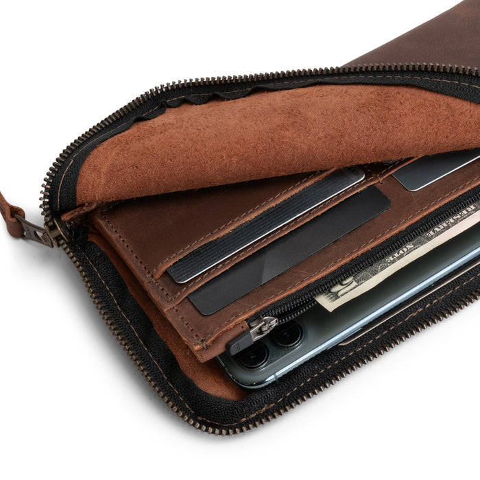 Close-up of the Large Zippered Wallet by Hide & Drink, featuring its zipper detail and Full Grain Leather texture. This Long Zippered Wallet for Men and Women works as a Card Holder, Card Organizer, and Bill Holder, making it an essential Travel Accessory. Each wallet is handmade through small batch production in La Antigua Guatemala & Oaxaca Mexico, showcasing artisan skills.