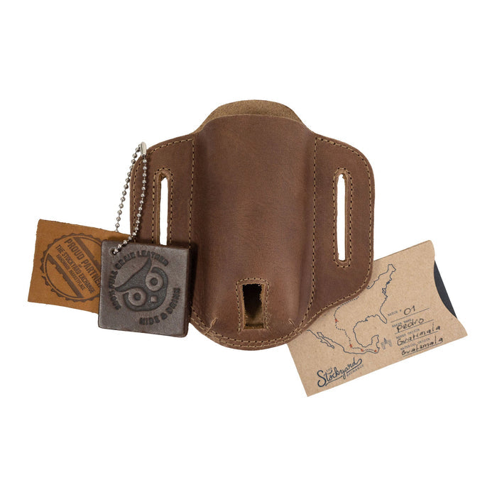 Tag accompanying the brown Multitool Belt Sheath from Hide & Drink, showcasing its artisan roots. This pocket knife set case is a durable outdoor accessory made from high-quality full grain leather, ideal for everyday carry.