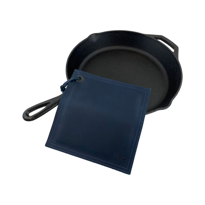 Hide & Drink Pot Pad alongside a cast iron skillet, emphasizing durability and functionality. This artisan-crafted hot pot pad is made from full grain leather.