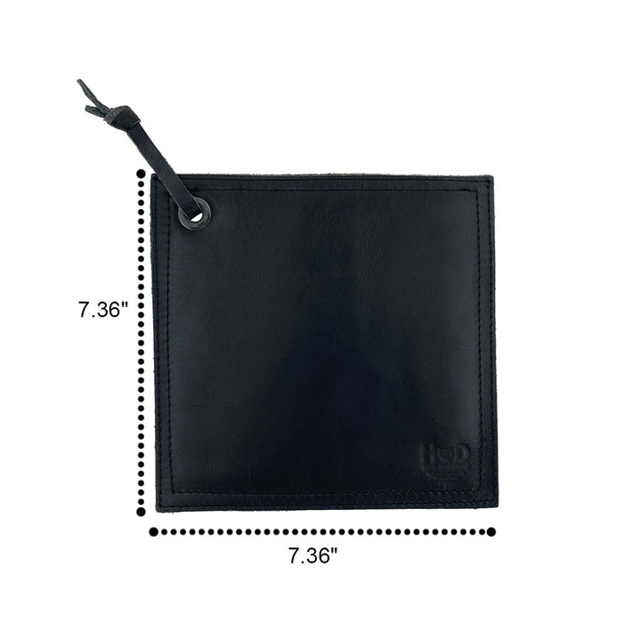 Hide & Drink Pot Pad in dark leather with a rustic appearance showcased next to cookware. Artisan crafted, it offers durable protection against heat.