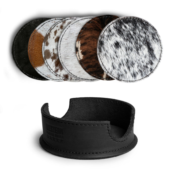 An assortment of hair-on-hide coasters presented with their storage holder from Western Leather Works, featured in the Set of 6 Circular Coasters for Drinks. These coasters are perfect for Glass & Cups Stain Protection, crafted from Full Grain Leather, reflecting the small batch production ethos and showcasing meticulous hand cut and hand sewn craftsmanship, with fire branding that denotes their artisan origin from La Antigua Guatemala & Oaxaca Mexico.