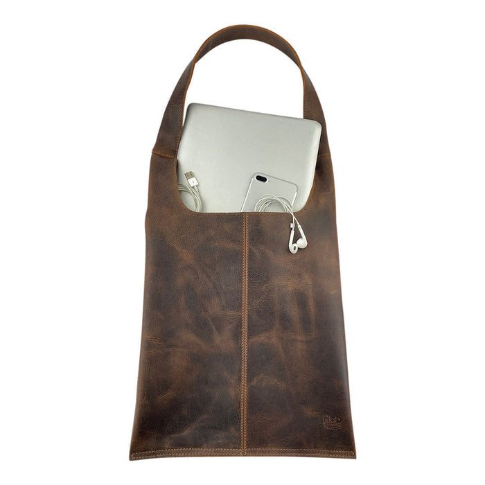 Shoulder Bag for Laptop by Hide & Drink with a laptop and phone, showcasing its practical design for modern travelers. Made from high-quality full grain leather, this bag is hand cut and sewn by artisans in La Antigua Guatemala.