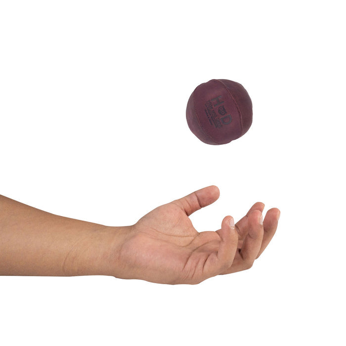 Hide & Drink maroon Stress Ball caught mid-flight, ideal for relieving fidgeting and anxiety. This squishy tension accessory highlights classic styling and is handmade from full grain leather in La Antigua Guatemala.