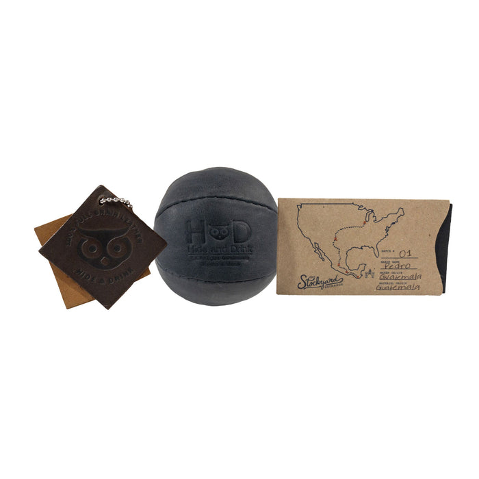 Hide & Drink black Stress Ball with packaging, signifying its quality as a gift option. This squishy tension accessory is great for relieving fidgeting and anxiety, made with full grain leather artisan crafted in La Antigua Guatemala.
