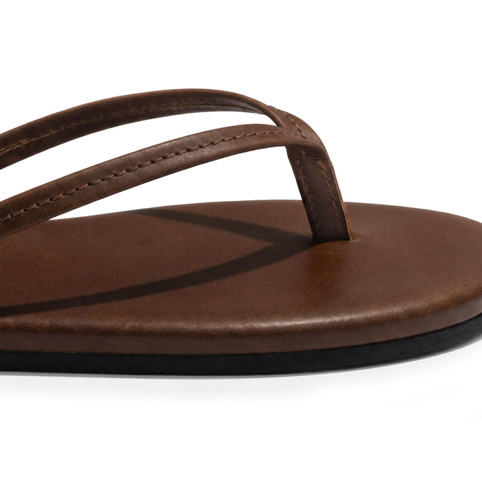 Close-up of the stitched leather thong and cushioned footbed on La Leche The Solana Leather Flip Flop (Women's); The Solana Leather Flip Flop (Women's), Full Grain Leather, StockyardX, Small Batch Production, Hand Cut, Hand Sewn, Fire Branded, Artisan, Handmade in La Antigua Guatemala & Oaxaca Mexico.