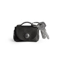 A stylish Tiny Handbag Keychain in black leather by Hide & Drink, featuring a key ring holder. This functional piece is made from high-quality Full Grain Leather and emphasizes small batch production and meticulous artisan craftsmanship.