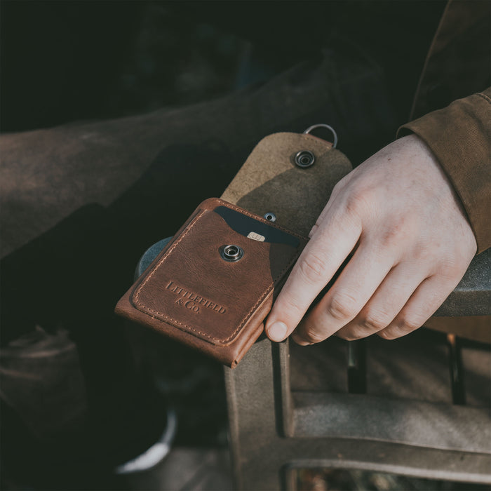 The Vintage Adventure Wallet by Littlefield Chicago is presented alongside a business card, emphasizing its practical yet stylish design. This full grain leather wallet acts as a compact men's bill organizer, ideal for travel accessories. Hand cut and hand sewn, it showcases the artisan production from La Antigua Guatemala & Oaxaca Mexico.
